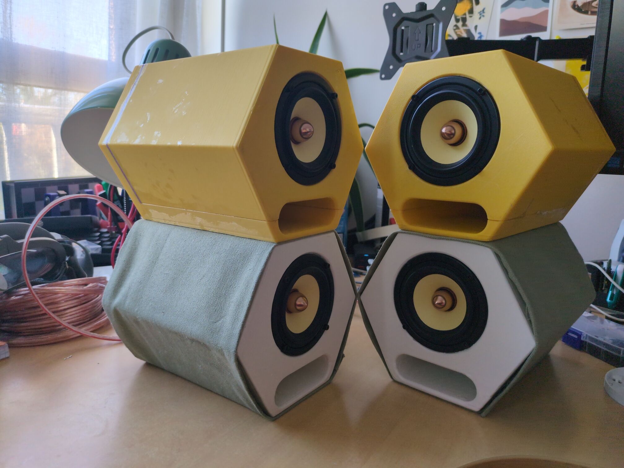 Two pairs of speakers, the bottom one wrapped in fabric and the top one simply printed in yellow